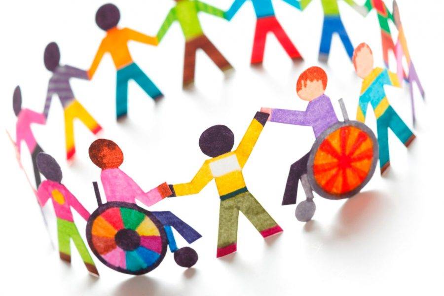 Uma roda com crianças ,duas estão em cadeiras de rodas e todas estão segurando a mão umas das outras.Vestem roupas coloridas.